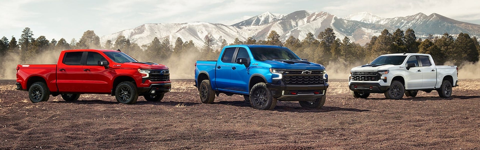 Three Chevy Silverados, parked with mountains in the back drop